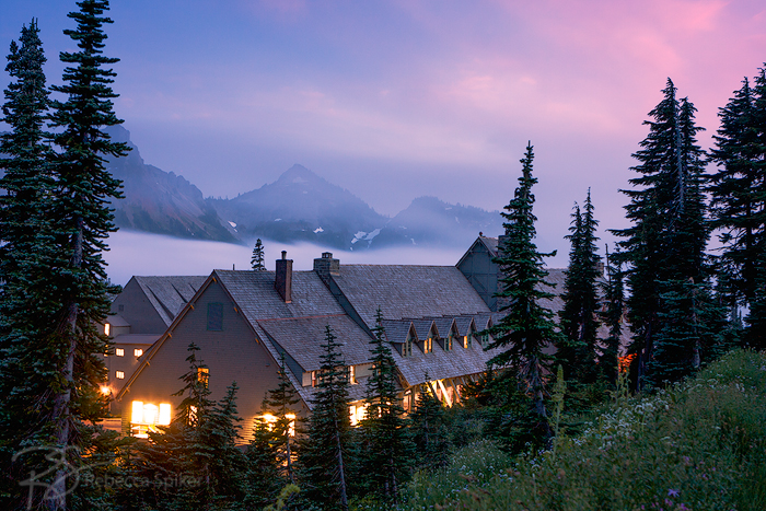 A blanket of fog painted pink by the late-day sun slowly encroaches on Paradise Inn at  Mount Rainier National Park.